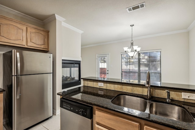 kitchen featuring sink, decorative light fixtures, light tile patterned floors, appliances with stainless steel finishes, and a notable chandelier