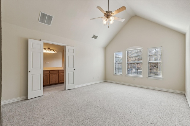 unfurnished bedroom featuring ceiling fan, ensuite bath, high vaulted ceiling, and light carpet