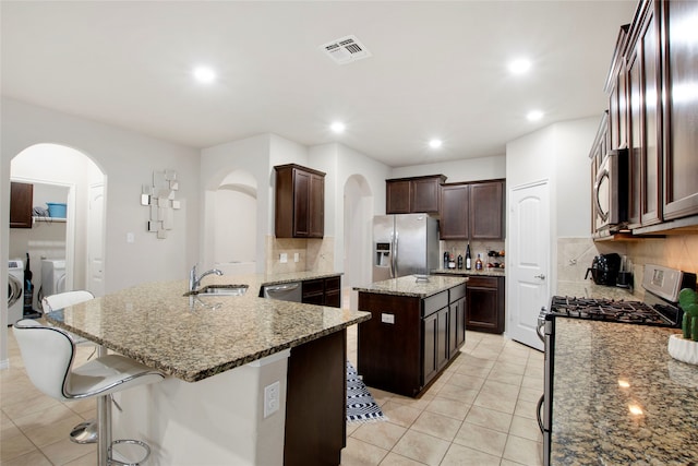 kitchen with decorative backsplash, stainless steel appliances, sink, separate washer and dryer, and a kitchen island