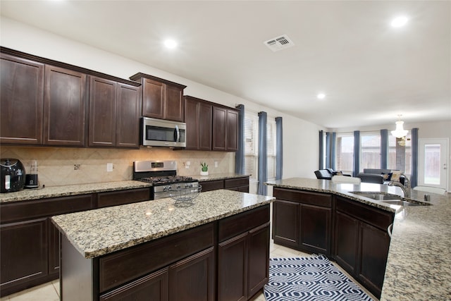 kitchen with sink, a center island, stainless steel appliances, an inviting chandelier, and decorative backsplash