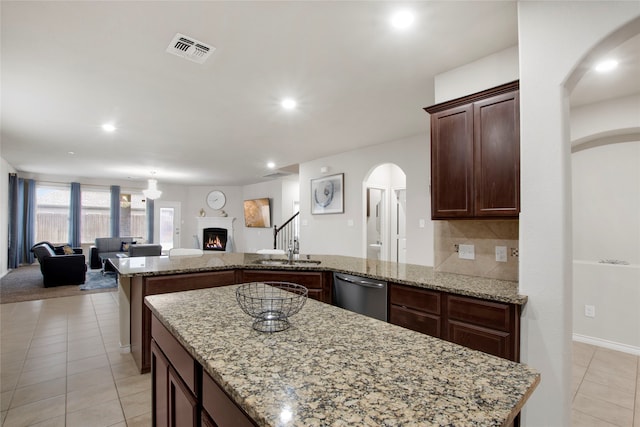 kitchen featuring dishwasher, light stone counters, and decorative backsplash