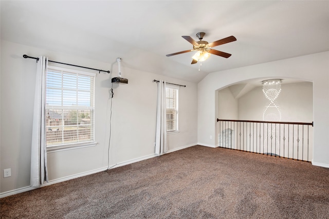 carpeted empty room with ceiling fan with notable chandelier and lofted ceiling