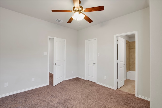 unfurnished bedroom featuring ceiling fan, light carpet, and ensuite bath