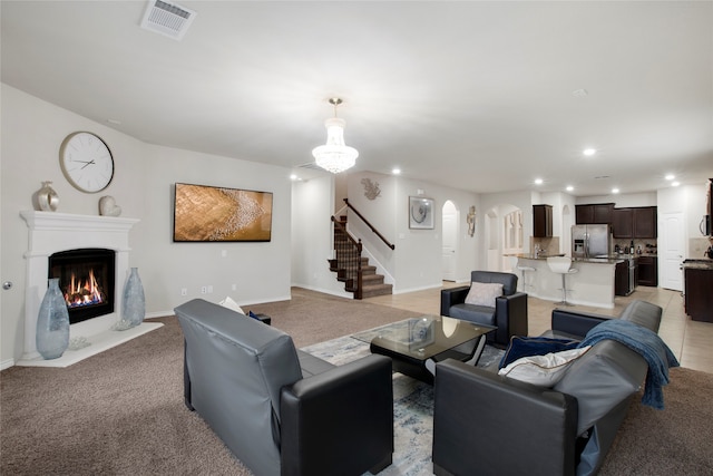 carpeted living room featuring an inviting chandelier