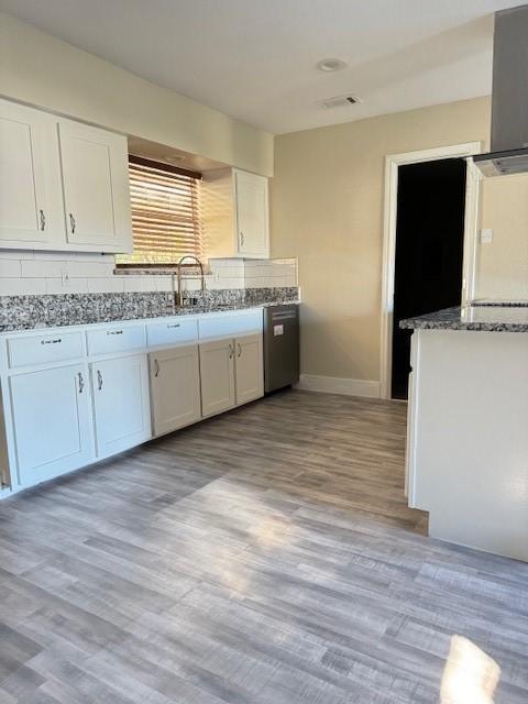 kitchen featuring white cabinets, light stone countertops, and light wood-type flooring