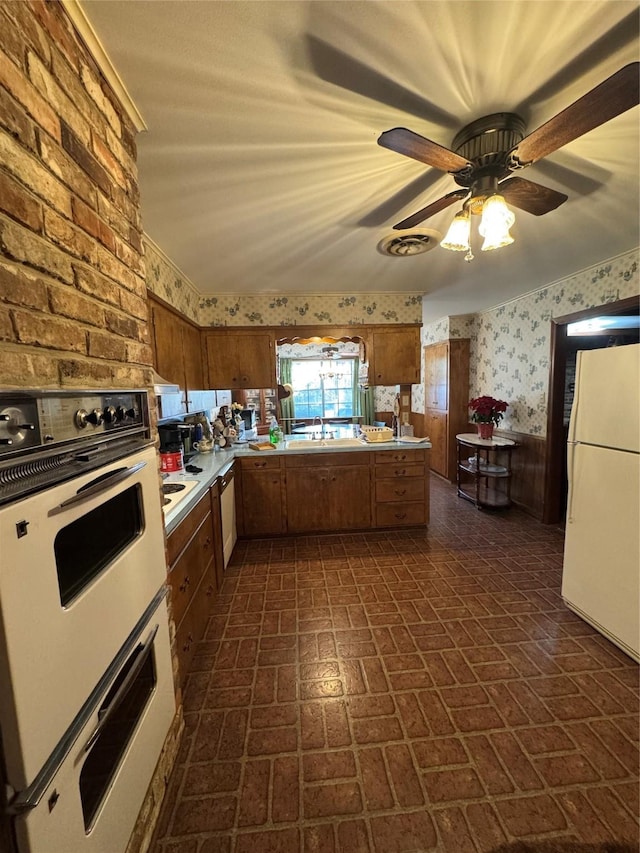 kitchen with kitchen peninsula, ceiling fan, sink, and white appliances