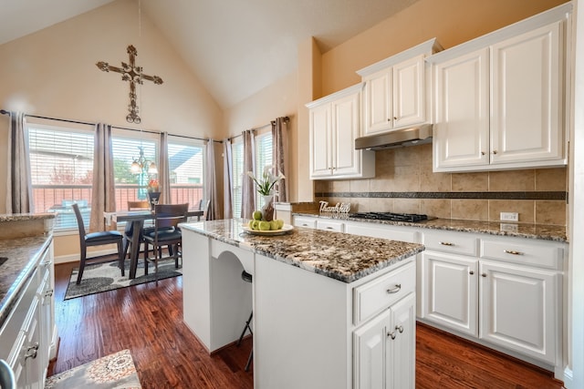 kitchen with stone counters, white cabinetry, a kitchen island, and gas cooktop