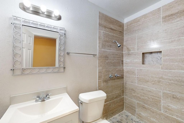 bathroom with vanity, toilet, and a tile shower