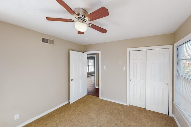 unfurnished bedroom with ceiling fan, multiple windows, light carpet, and a closet