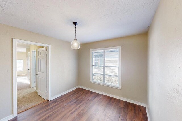 empty room with a textured ceiling and dark hardwood / wood-style floors