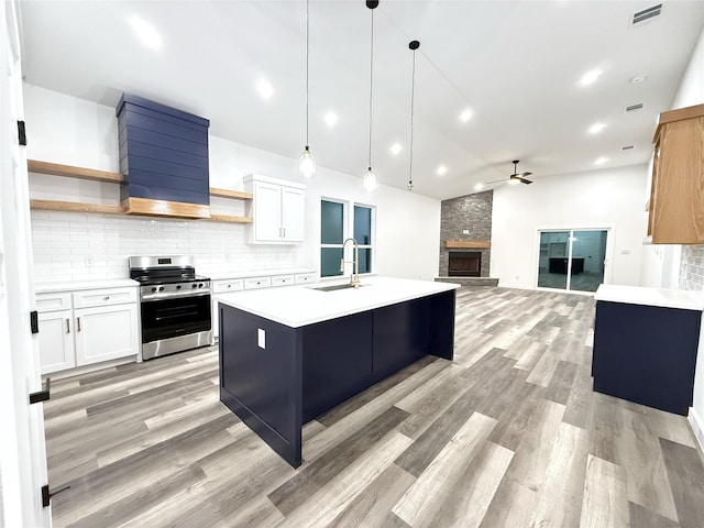 kitchen with pendant lighting, ceiling fan, stainless steel range oven, and white cabinetry