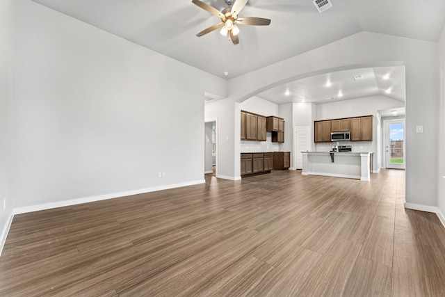 unfurnished living room with hardwood / wood-style floors, ceiling fan, and vaulted ceiling