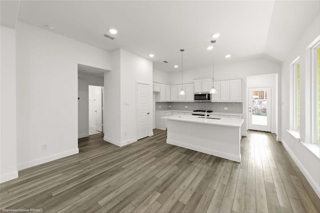 kitchen with white cabinetry, sink, hardwood / wood-style floors, and a center island with sink