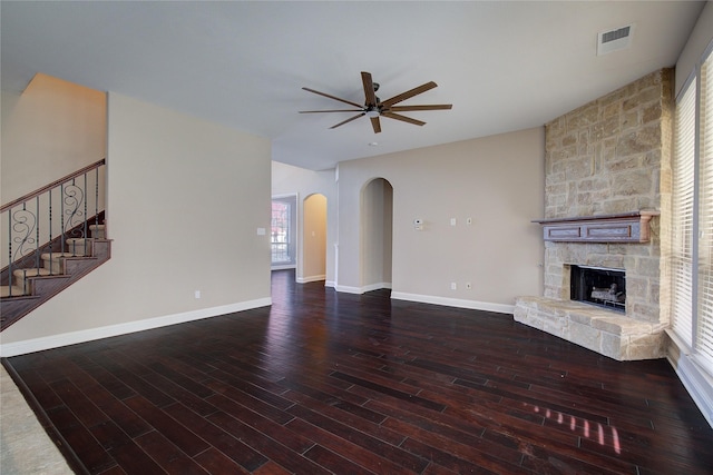 unfurnished living room with hardwood / wood-style flooring, ceiling fan, a healthy amount of sunlight, and a stone fireplace