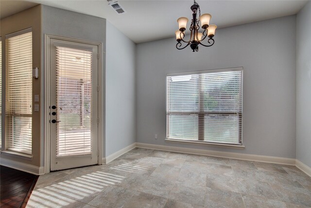 unfurnished dining area with a notable chandelier, baseboards, visible vents, and stone finish floor