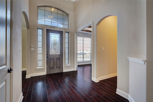 entryway with arched walkways, baseboards, and hardwood / wood-style flooring