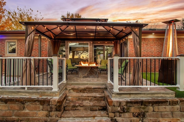 deck at dusk with a gazebo and a fire pit