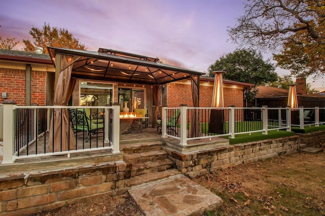 back house at dusk featuring a gazebo