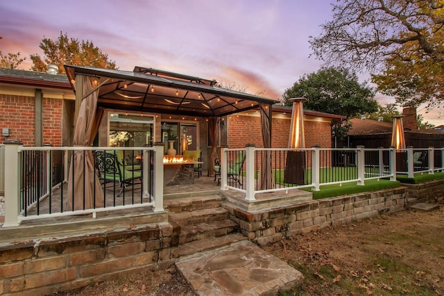 back house at dusk featuring a gazebo