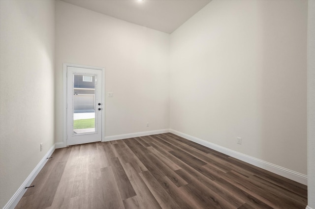 empty room with dark hardwood / wood-style flooring and high vaulted ceiling