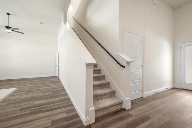 stairs with hardwood / wood-style flooring, high vaulted ceiling, and ceiling fan