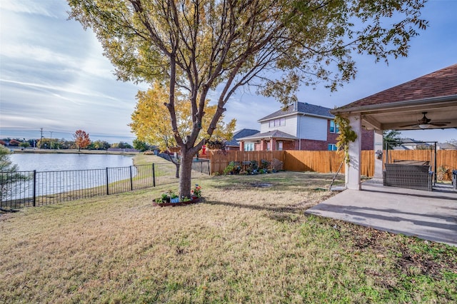 view of yard featuring ceiling fan, a water view, and a patio