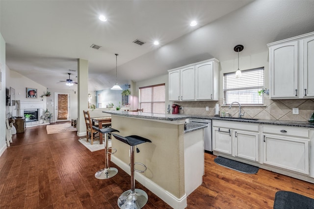 kitchen with pendant lighting, sink, white cabinetry, and a kitchen island