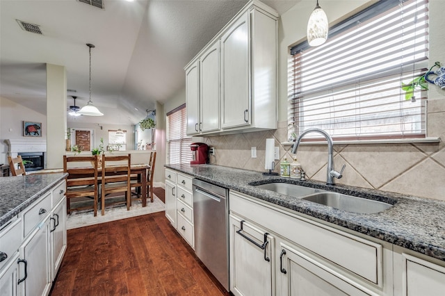 kitchen with lofted ceiling, sink, decorative light fixtures, dishwasher, and white cabinets