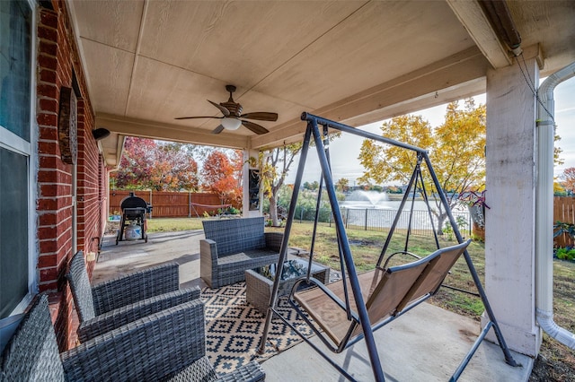 view of patio with an outdoor living space, a playground, ceiling fan, and a water view