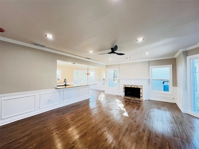 unfurnished living room featuring ornamental molding, ceiling fan, dark wood-type flooring, and sink