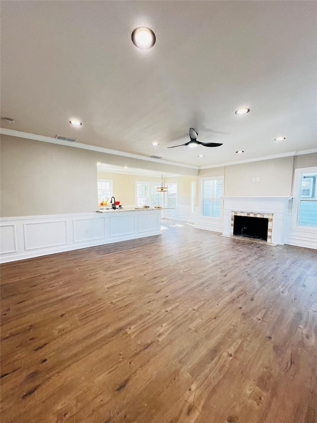 unfurnished living room featuring sink, hardwood / wood-style flooring, ornamental molding, and ceiling fan