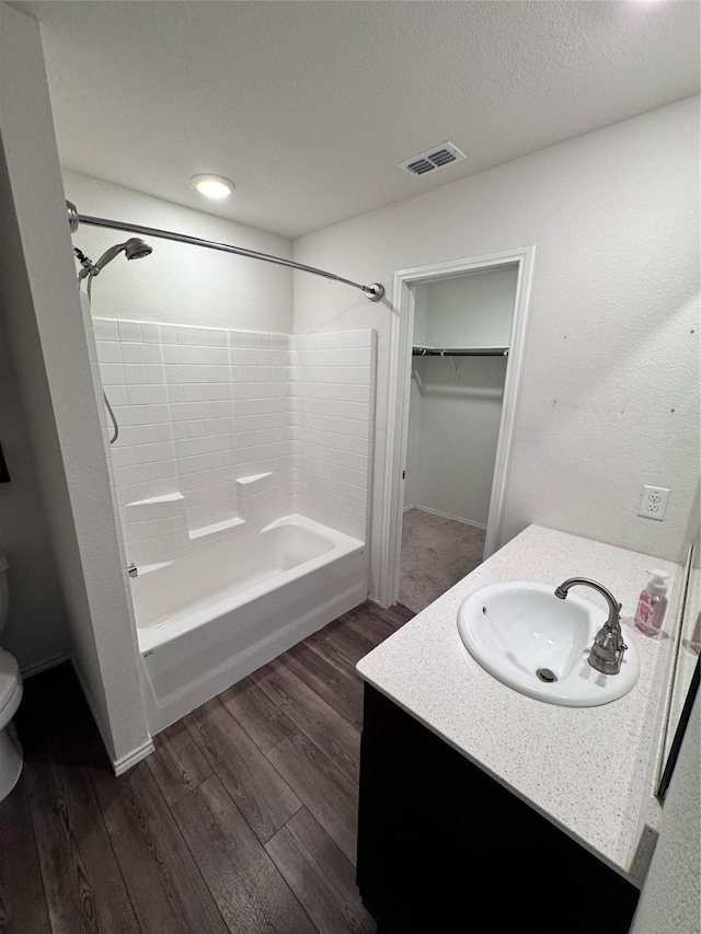 full bathroom with hardwood / wood-style floors, vanity, toilet, bathing tub / shower combination, and a textured ceiling