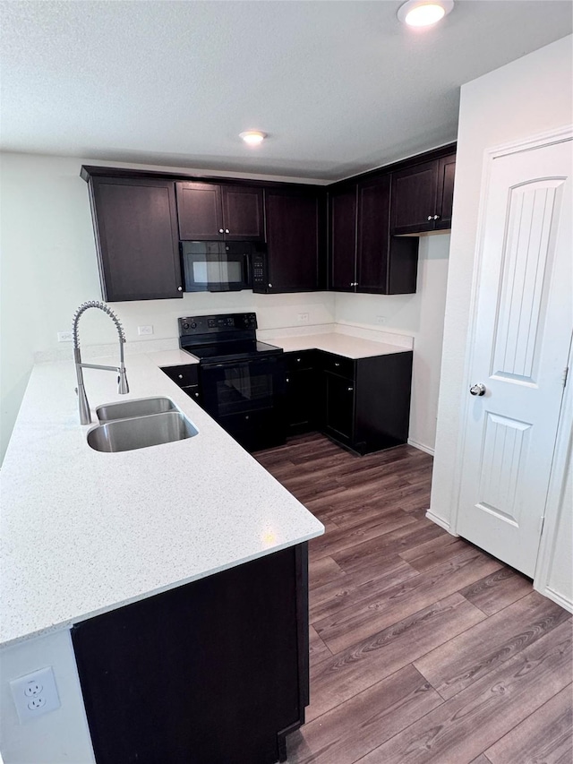 kitchen with sink, hardwood / wood-style flooring, dark brown cabinetry, black appliances, and a textured ceiling