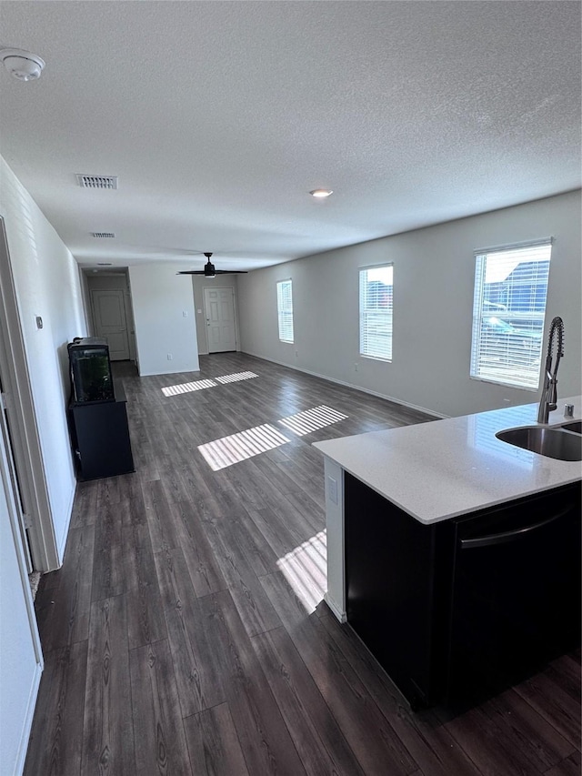 unfurnished living room with ceiling fan, sink, a textured ceiling, and dark hardwood / wood-style floors