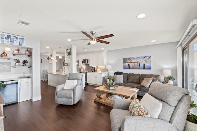 living room with dark wood-type flooring, bar area, and ceiling fan