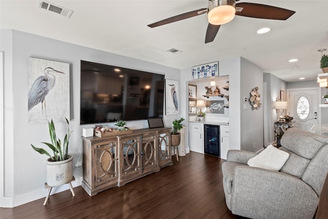 living room with wine cooler, dark wood-type flooring, ceiling fan, and bar