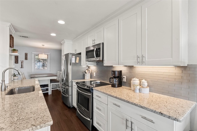 kitchen featuring sink, hanging light fixtures, stainless steel appliances, light stone countertops, and white cabinets