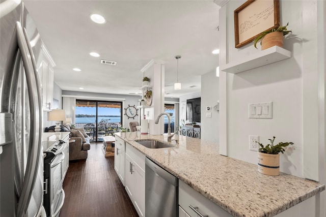 kitchen with appliances with stainless steel finishes, sink, white cabinets, hanging light fixtures, and light stone countertops