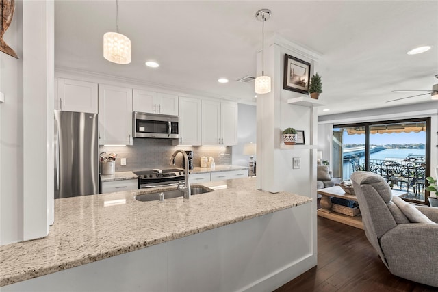 kitchen with appliances with stainless steel finishes, decorative light fixtures, sink, white cabinets, and light stone countertops