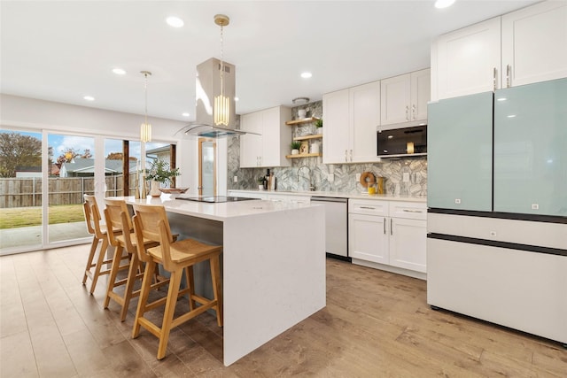 kitchen with white cabinets, island range hood, white fridge, and hanging light fixtures