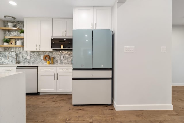 kitchen with stainless steel dishwasher, white fridge, light hardwood / wood-style floors, backsplash, and white cabinets