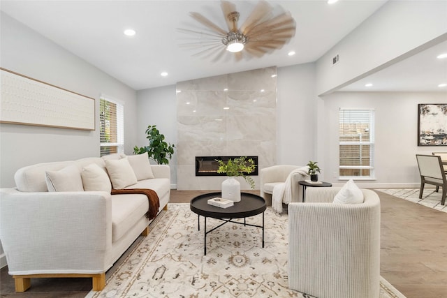 living room featuring a wealth of natural light, light wood-type flooring, a high end fireplace, and lofted ceiling