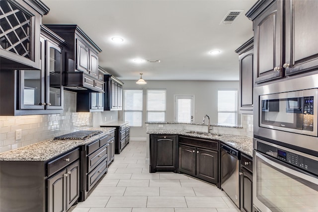 kitchen with tasteful backsplash, sink, dark brown cabinets, and stainless steel appliances