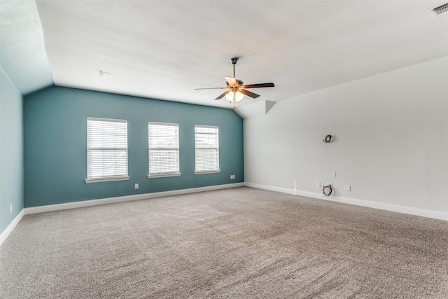 empty room with lofted ceiling, ceiling fan, and carpet flooring