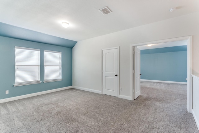 carpeted empty room with vaulted ceiling