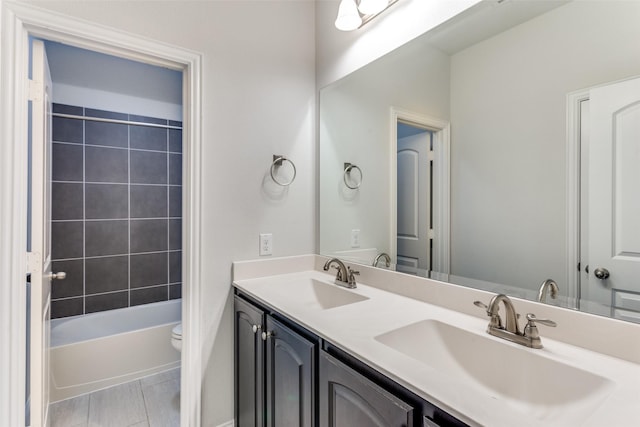 full bathroom with vanity, tiled shower / bath, and toilet