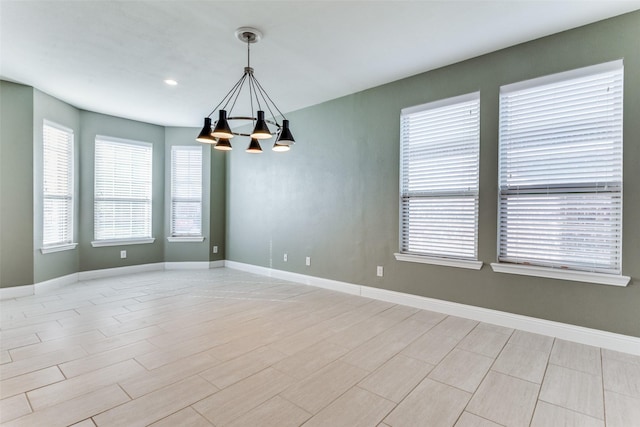 spare room featuring a chandelier and light hardwood / wood-style floors