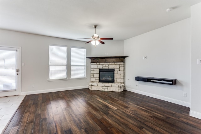 unfurnished living room featuring ceiling fan, dark wood-type flooring, and a fireplace