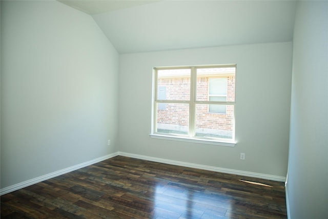 spare room featuring dark wood-type flooring and vaulted ceiling