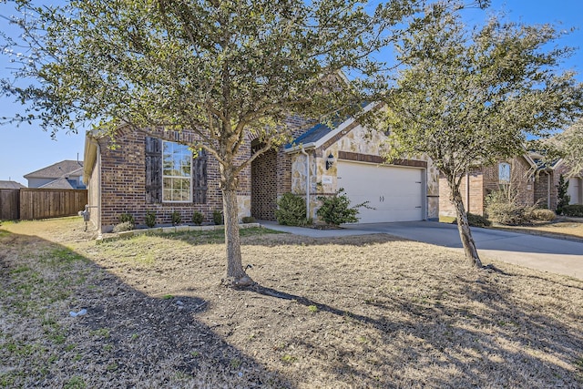 view of property hidden behind natural elements featuring brick siding, driveway, a garage, and fence